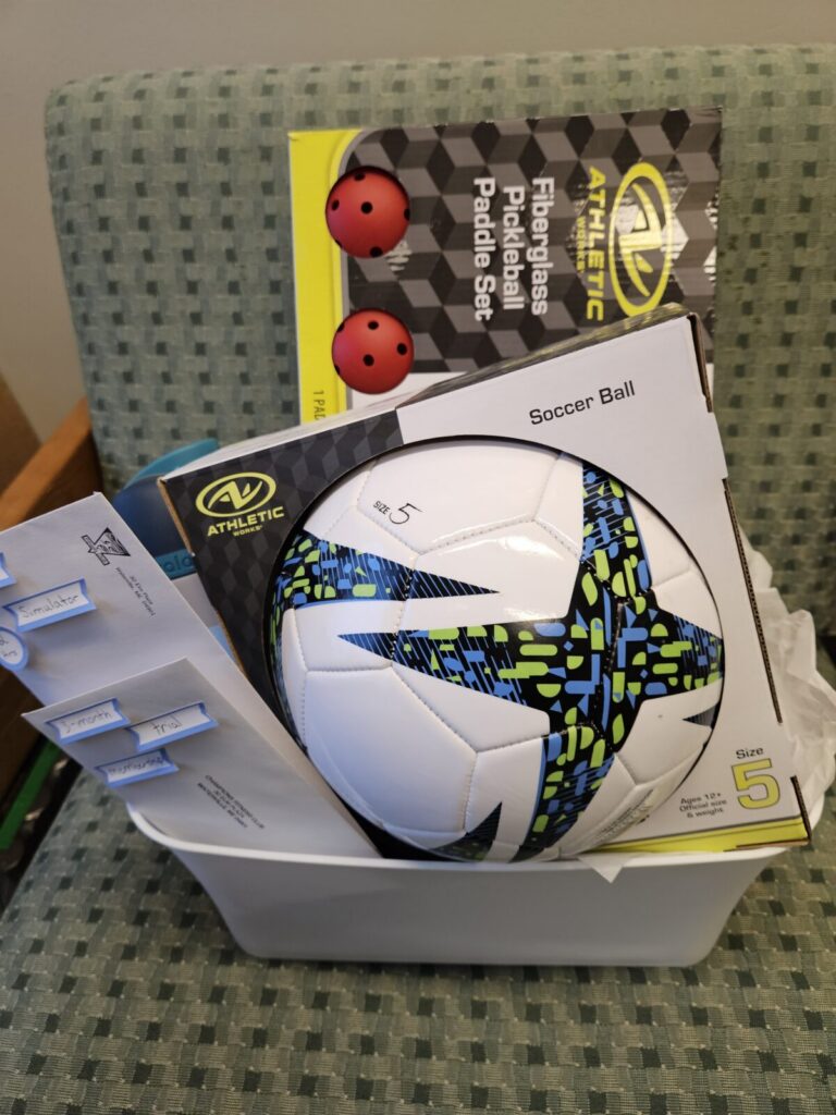 Picture of a sports themed gift basket with a soccer ball and other sports related items.