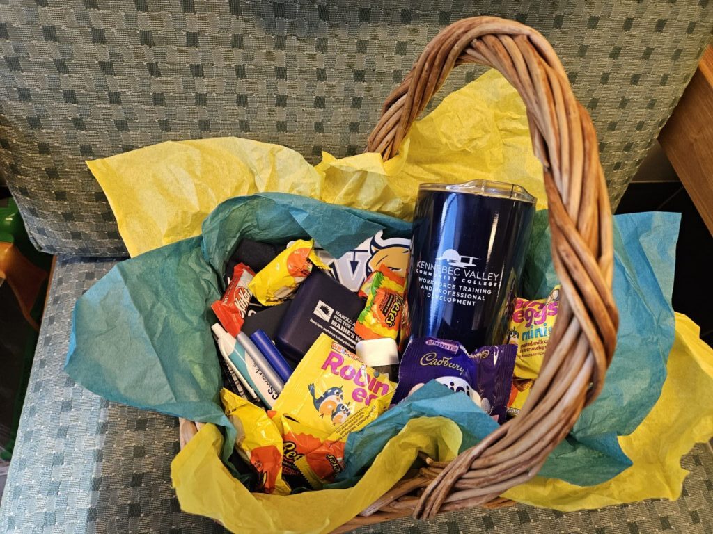 A gift basket filled with candy, a KVCC branded travel mug, and other KVCC branded swag.