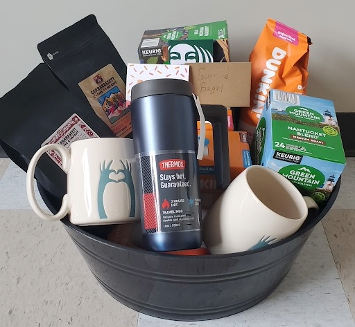 Basket filled with various types of coffee, coffee mugs, and gift cards.